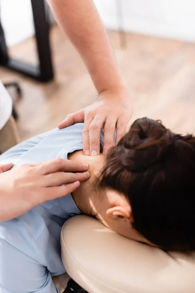 Close up view of masseur doing seated massage of neck for businesswoman on blurred background — Stock Photo