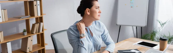 Trabajadora de negocios con cuello doloroso sentada en el lugar de trabajo en la oficina, pancarta - foto de stock