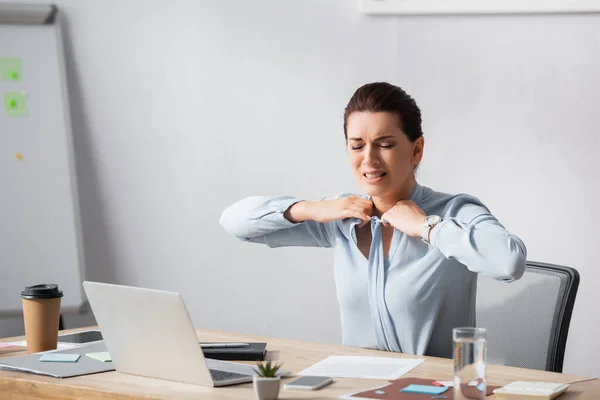 Irritierte Geschäftsfrau löst Bluse auf, während sie am Arbeitsplatz im Büro sitzt — Stockfoto