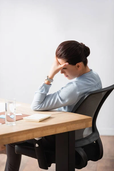 Уставшая деловая женщина с головной болью, опирающаяся на рабочее место, сидя на офисном стуле — стоковое фото