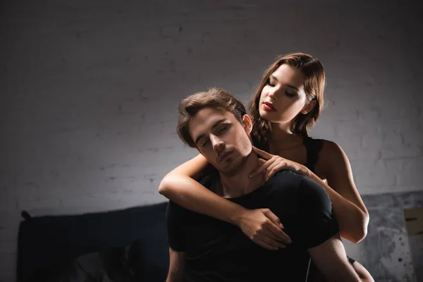 Sensual woman with red lips hugging boyfriend at home during evening — Stock Photo