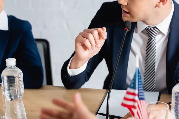 Cropped view of man in formal wear gesturing, while speaking in microphone on blurred foreground — Stock Photo