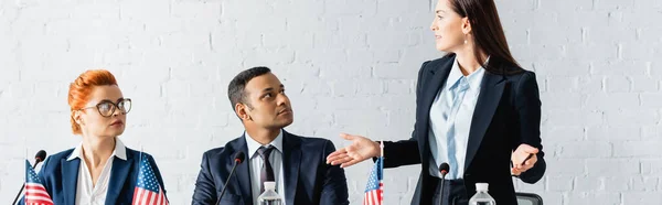 Femme politique à bras ouverts regardant des collègues multiculturels assis dans la salle de conférence, bannière — Stock Photo