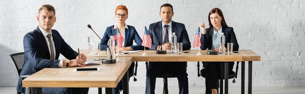 Political party members looking at camera, while sitting at table in boardroom, banner — Stock Photo