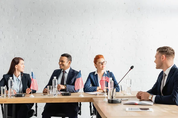 Políticos en parejas mirándose, mientras hablan durante la reunión del partido político en la sala de juntas - foto de stock