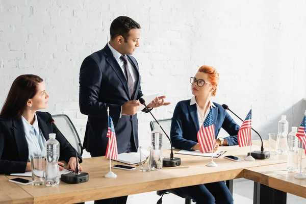 Politiche donne che guardano la collega indiana in piedi con tablet digitale in sala riunioni, durante la riunione del partito politico — Foto stock