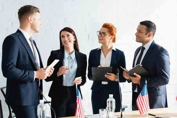 Politici multiculturali sorridenti che guardano il membro del partito politico in piedi in sala riunioni — Foto stock