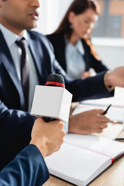 Vista ritagliata del giornalista con microfono intervistando politico indiano durante la conferenza stampa su sfondo sfocato — Foto stock