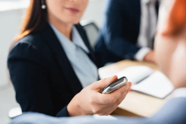 Cropped view of journalist with dictaphone interviewing politician during press conference on blurred background — Stock Photo