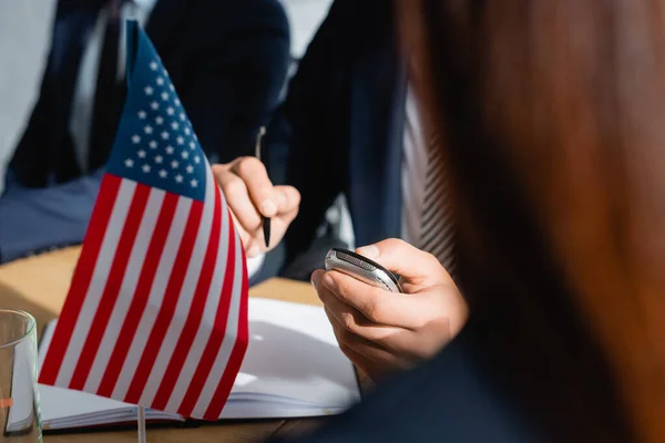 Partial view of journalist with dictaphone holding pen while interviewing politicians during press conference, blurred foreground — Stock Photo