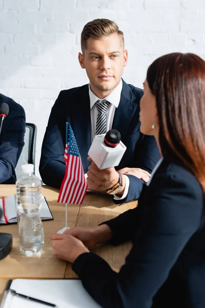 Journalist mit Mikrofon interviewt Politiker bei Pressekonferenz zu verschwommenem Hintergrund — Stockfoto