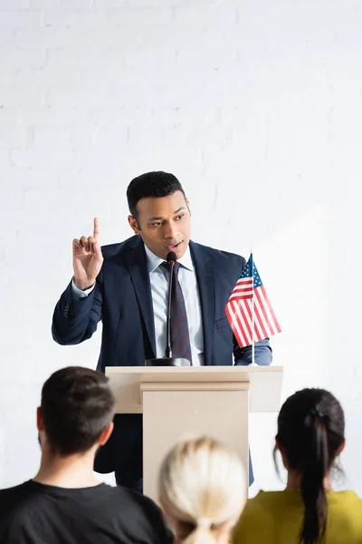 Indian political agitator showing attention gesture while talking to electors in conference hall, blurred foreground — Stock Photo