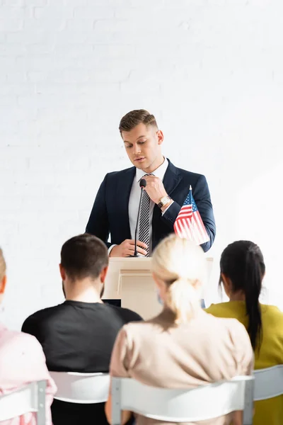 Confident political agitator standing in front of voters in conference hall, blurred foreground — Stock Photo