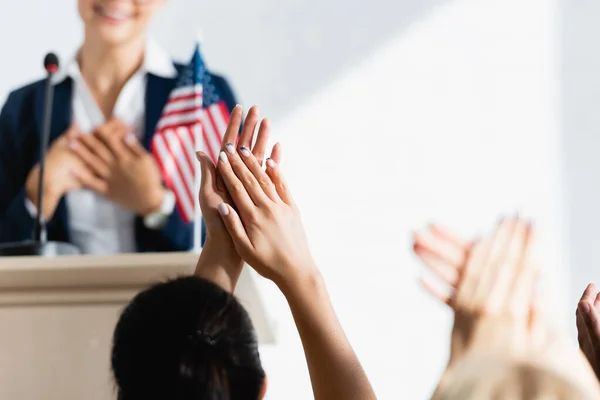 Grateful political agitator holding hands on chest in front of voters iapplauding n conference room, blurred foreground — Stock Photo