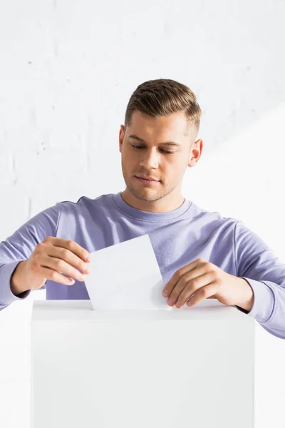 Hombre insertando papeleta en la cabina de votación - foto de stock