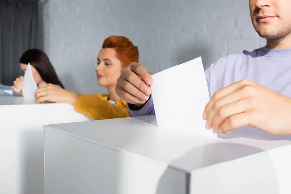 Wahlhelfer, die Stimmzettel auf verschwommenem Hintergrund in Wahlurnen einwerfen — Stockfoto