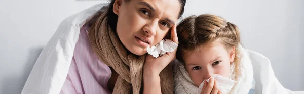 Mujer enferma con hija con servilletas de papel mirando a la cámara, pancarta - foto de stock