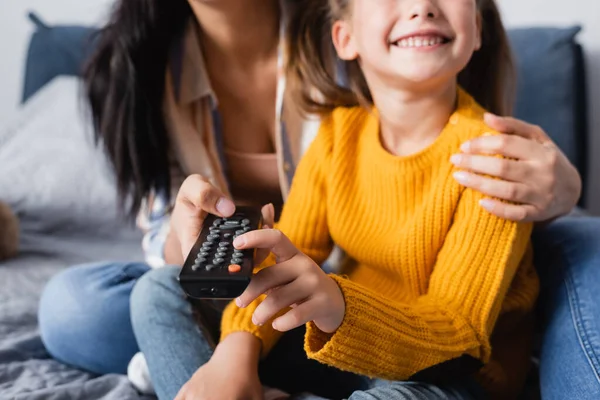 Vue recadrée de heureux enfant regarder la télévision avec la mère sur fond flou — Photo de stock