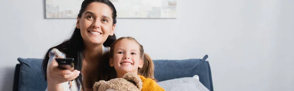 Cheerful mother and daughter watching tv together at home, banner — Stock Photo