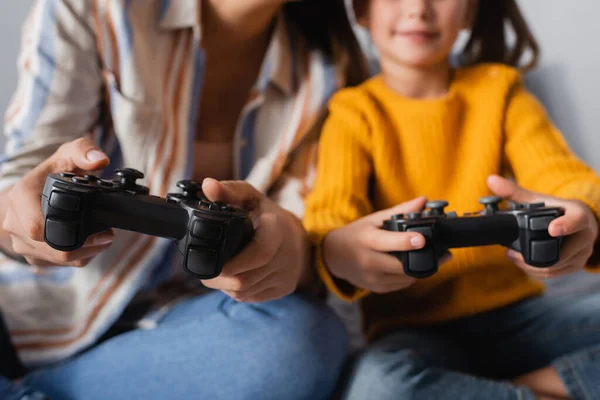 KYIV, UKRAINE - 15 SEPTEMBRE 2020 : vue recadrée du jeu mère-fille avec des joysticks sur fond flou, bannière — Photo de stock