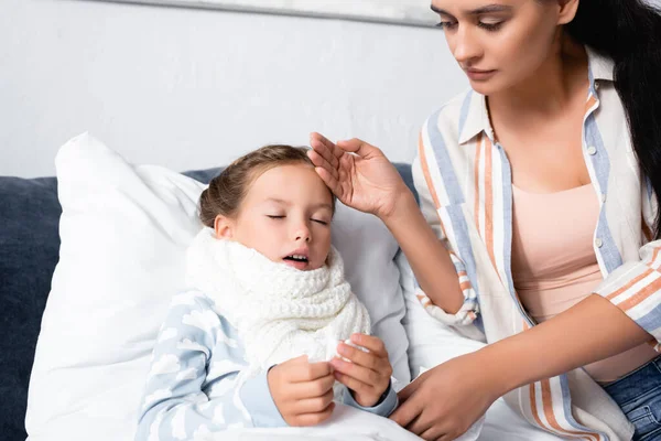 Frau berührt Stirn kranker Tochter, die mit geschlossenen Augen im Bett liegt — Stockfoto