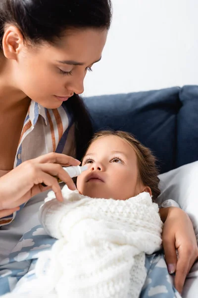 Femme utilisant pulvérisation nasale tandis que la fille malade couché dans le lit — Photo de stock