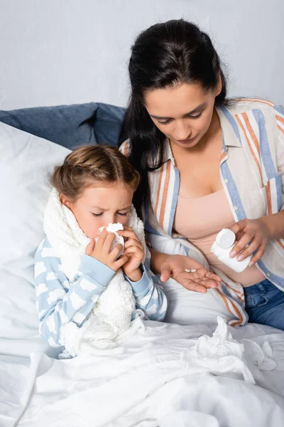 Frau behandelt kranke Tochter, die in Papierserviette niest — Stockfoto