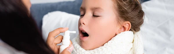 Mother curing sick girl with throat spray on blurred foreground, banner — Stock Photo