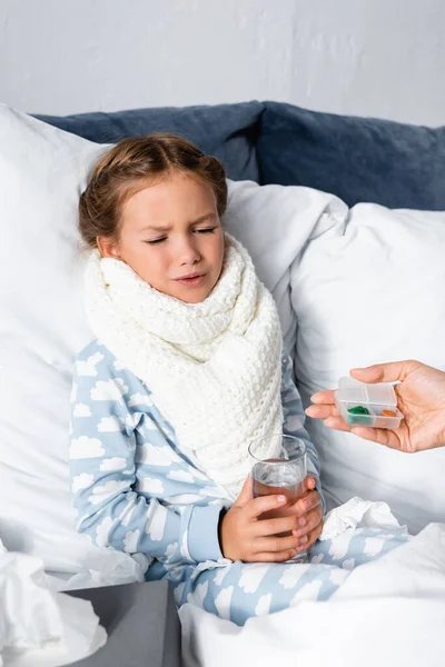 Mère donner des pilules à malade, fille mécontente tenant verre d'eau — Photo de stock