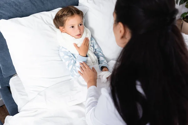 Vue grand angle du médecin touchant fille malade couchée dans le lit à la maison — Photo de stock