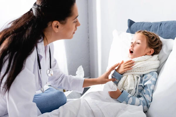 Pédiatre examen mal de gorge de la fille malade couché dans le lit — Photo de stock