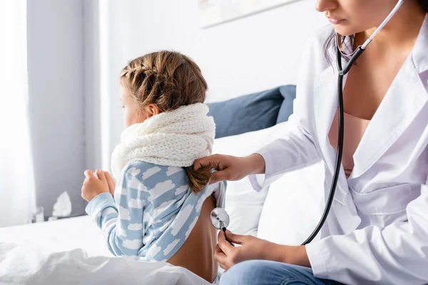 Arzt untersucht krankes Mädchen im Bett sitzend mit Stethoskop — Stockfoto