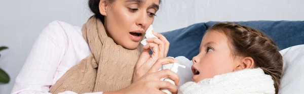 Mujer enferma sosteniendo spray de garganta cerca de hija enferma, pancarta - foto de stock