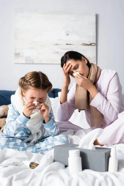 Mère malade et enfant souffrant de nez qui coule et éternuant dans des serviettes en papier — Photo de stock