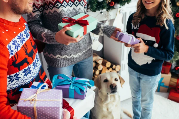 Cropped view of parents holding gifts near happy daughter and dog on christmas — Stock Photo