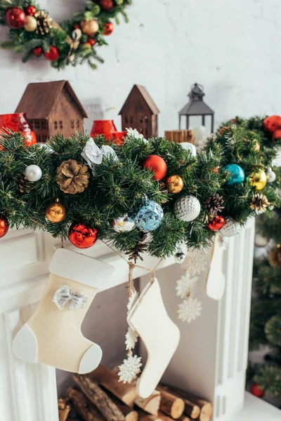 Bolas coloridas no pinheiro perto de meias de Natal perto da lareira — Fotografia de Stock