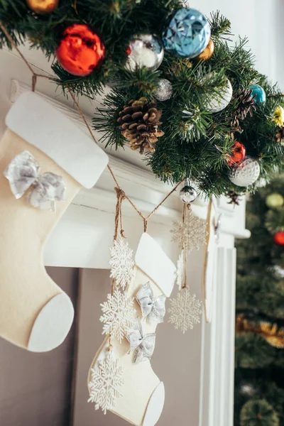 Palline colorate e pigne su abete vicino a calze natalizie e camino — Foto stock
