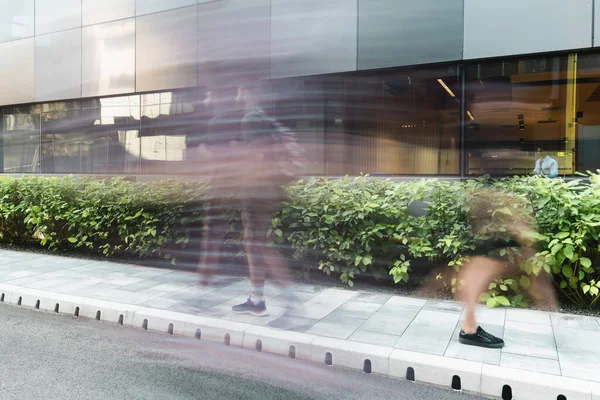 Motion blur of people walking on urban street near modern building — Stock Photo