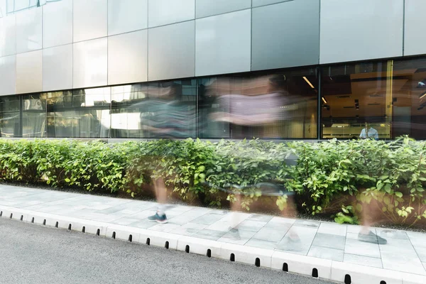 Langzeitbelichtung von Menschen, die auf städtischen Straßen in der Nähe moderner Gebäude gehen — Stockfoto