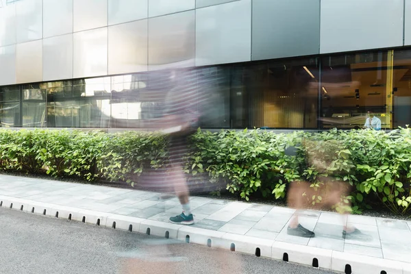 Motion blur of people walking on street near modern building — Stock Photo