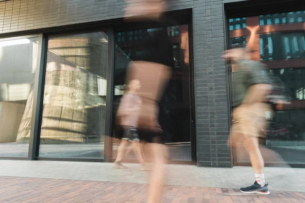 Citizens walking on modern street near building, long exposure — Stock Photo