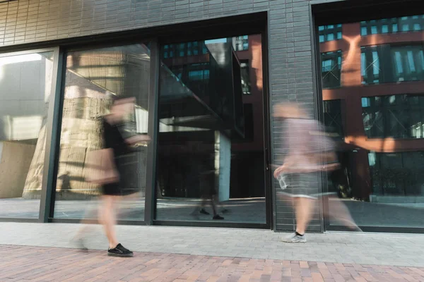 Flou de mouvement des citoyens marchant sur la rue moderne près du bâtiment — Photo de stock