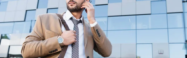 Partial view of bearded businessman adjusting wireless earphones outside, banner — Stock Photo