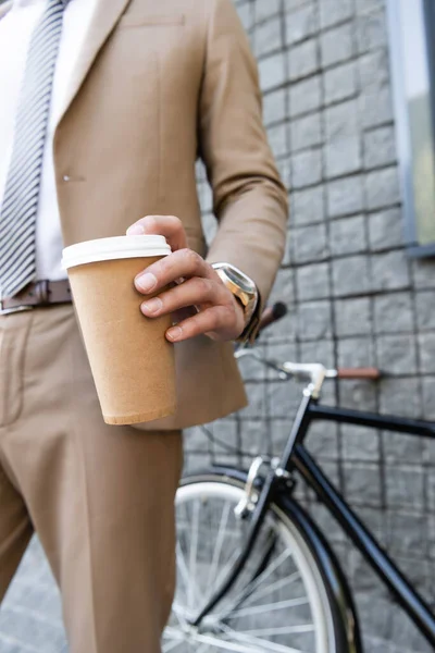 Cropped view of businessman in suit holding coffee to go near building — Stock Photo