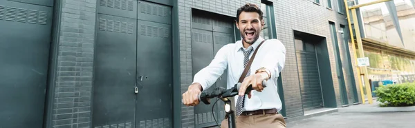 Hombre de negocios sorprendido en el desgaste formal montar scooter eléctrico, bandera - foto de stock