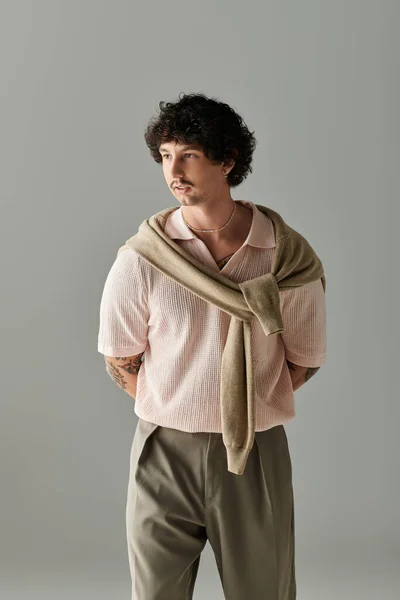Schöner junger Mann steht elegant und verbindet lässigen Stil mit raffiniertem Auftreten in weichen Farbtönen. — Stockfoto