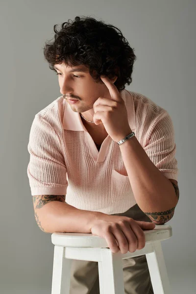 A handsome man exhibits a relaxed demeanor while posing in a modern setting filled with soft light. — Stock Photo