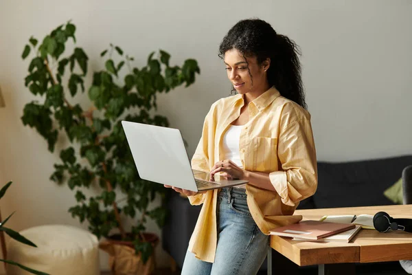 Красивая афроамериканка усердно работает на ноутбуке в современной квартире. — стоковое фото