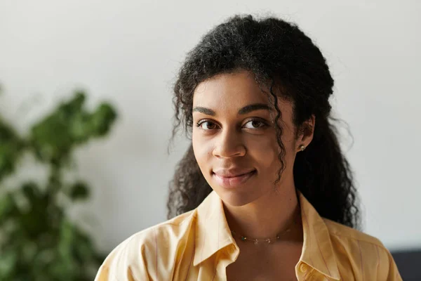 Портрет молодой африканской женщины с вьющимися волосами фокусируется на том, чтобы смотреть в камеру дома. — стоковое фото