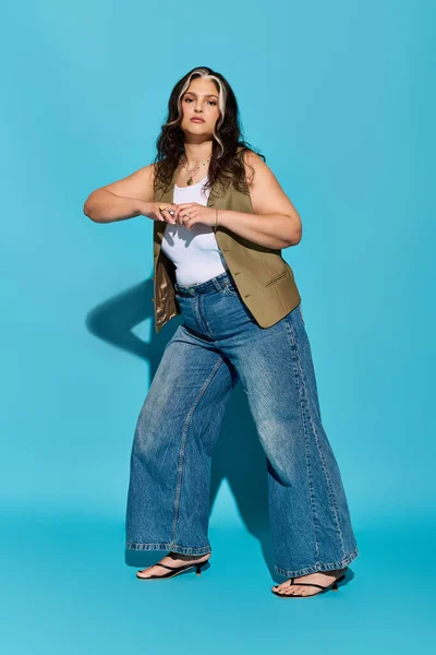 Una donna elegante posa con fiducia su uno sfondo blu vibrante, mostrando la sua unicità. — Foto stock